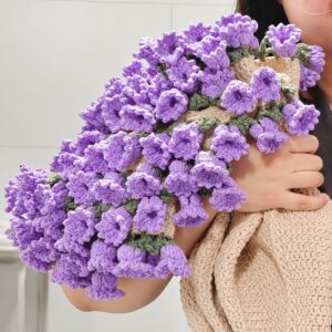 A crocheted blanket gathered into a bouquet and held over one shoulder, with lilac bell-shaped lilies and green leaves along the edge of a beige body