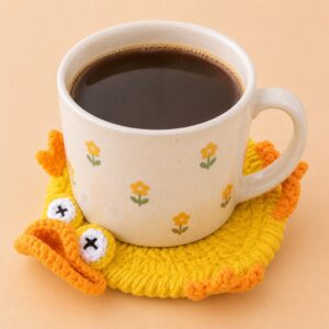 A duck coaster under a mug, its yellow rim, wings and big white eyes lifting up around the base of the cup