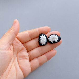 Two small crocheted eyes, white ovals edged in black, lying in an open hand