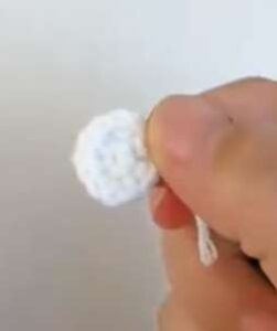 A small white crocheted circle for an eye, held between finger and thumb