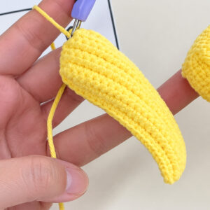 The yellow top of the body at round 8, held on the fingers with the hook in it: a round worked all the way round its edge, and the piece starting to curl up at the sides
